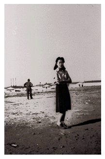 Woman in dust storm with camp in background — family album photograph from the Japanese American internment